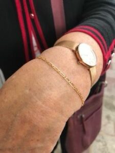 gold welded bracelet on wrist paired with simple gold watch